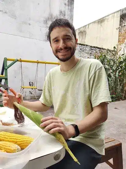 Rafael Greco debulhando milho colhido em quintal urbano